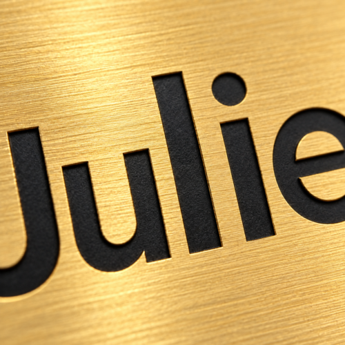 Close-up of black engraving on a brushed gold metal name tag